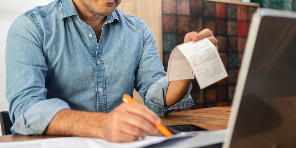 homem segurando nota fiscal e fazendo cálculo do capital de giro da empresa